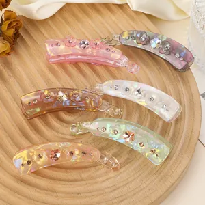 Vue détaillée de six pinces banane à fleurs avec strass dans un plateau en bois