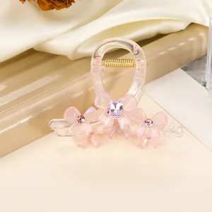 Detail of pink acrylic hair claw clip with bow accents and inlaid gemstones