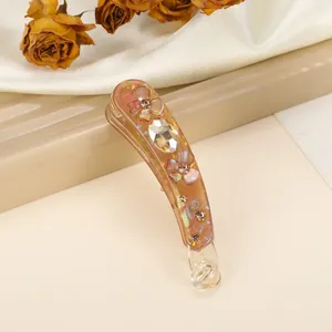 Detail of banana hair clip with iridescent amber finish and sparkling gemstone inlay