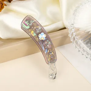 Détail de la pince à cheveux banane nacrée avec strass et décoration florale en 3D