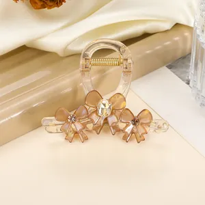 Detailed view of resin hair claw clip with bow designs and sparkling rhinestone accents