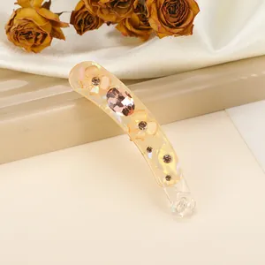 Detail of amber resin banana hair clip with floral relief and large oval gemstone inlay
