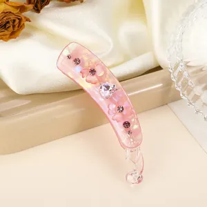 Detail van roze bananenklem met parelmoerglans en hartvormige strass-steentjes
