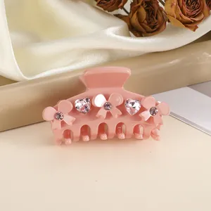 Detailed view of pink bow hair claw clip with heart rhinestones and flower accents