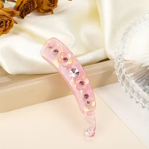 Détail d'une pince banane rose avec strass et fleurs 3D sur un tissu en soie