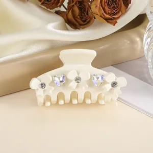 Detail of cream bow hair claw clip with crystal rhinestones on elegant silk background