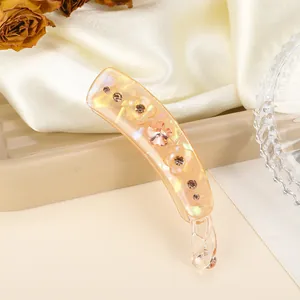 Vue détaillée d'une pince à cheveux orange avec strass sur tissu en soie beige
