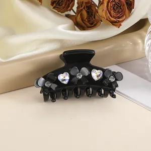 Macro shot of 5cm black hair claw clip with heart crystals and floral rhinestones