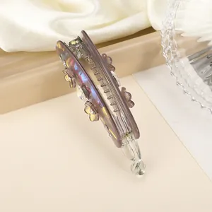 Détail de la pince à cheveux banane violette laser avec fleurs et strass étincelants