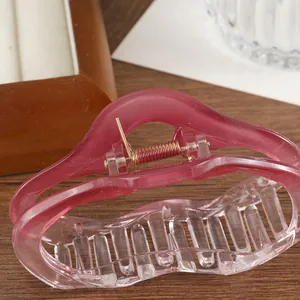 Pince à cheveux nuage dégradé rose en résine translucide sur table en bois