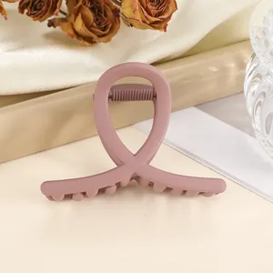 Close-up of matte Morandi pink hair claw clip with crossed design on silk fabric