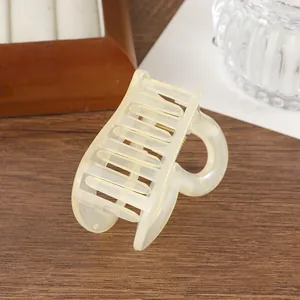Dettaglio di una molletta per capelli a cuore color crema su sfondo in legno rustico