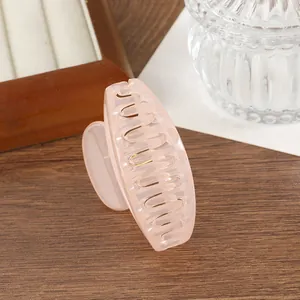 Détail d'une pince à cheveux rose translucide posée sur une table en bois