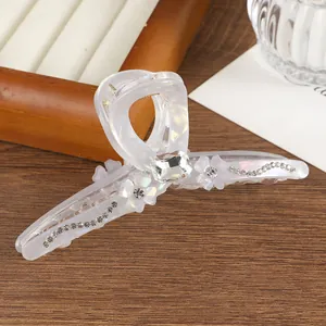 Detailed view of the large floral hair claw with sparkling rhinestones and pearl finish