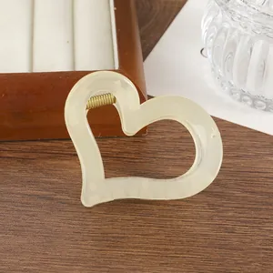 Dettaglio di un fermaglio per capelli a cuore cavo in resina crema con molla in metallo