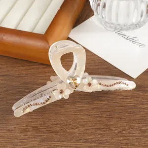 Macro-opname van parelwitte haarklem met amberkleurig hart en bloemige strass details