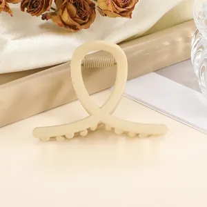 Macro detail of beige matte hair claw clip with cross design and internal metal spring