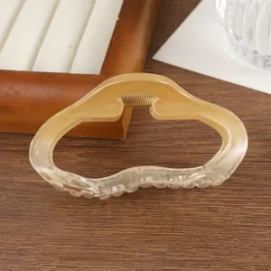 Détail d'une pince à cheveux ondulée ambre translucide avec un ressort en métal doré
