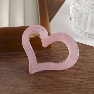 Dettaglio molletta per capelli a cuore rosa traslucido con molla in metallo dorato