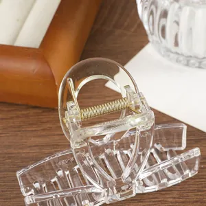 Pinza para el cabello transparente con muelle dorado para recogidos en fondo de madera