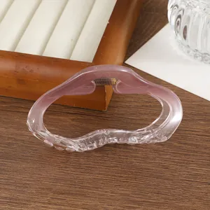 Gros plan détaillé d'une pince à cheveux rose dégradé ondulée sur présentoir en bois