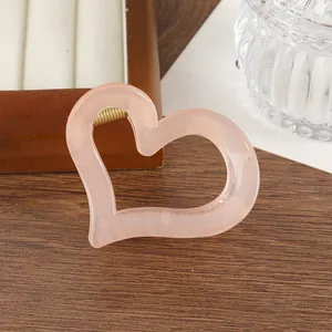 Dettaglio di un fermaglio per capelli a cuore rosa pesca con molla dorata su vassoio