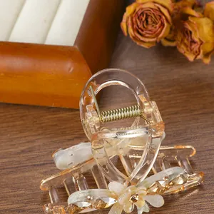 Elegante pinza para el pelo con flor ámbar y diamantes sobre fondo de madera