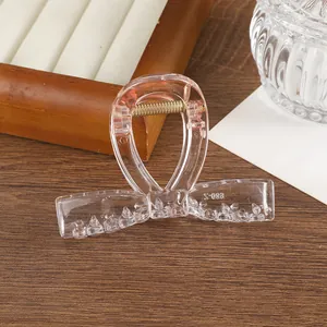 Detalle de pinza para el pelo de mariposa rosa transparente con muelle metálico dorado
