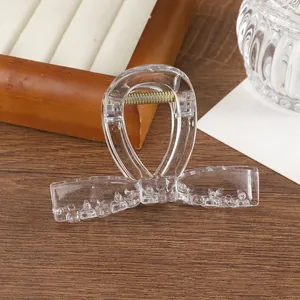 Primer plano de una pinza para el pelo transparente con lazo y muelle metálico dorado