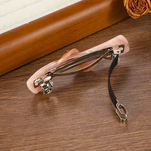 Pink marble acetate spring hair clip with silver metal clasp and anti-slip grip on wood