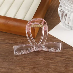 Detalle de pinza para el pelo con lazo rosa transparente y muelle dorado en bandeja