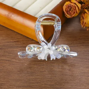 Detalle de una pinza para el pelo transparente con flores y pedrería sobre madera