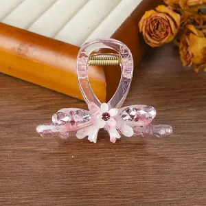 Detalle de la pinza para el cabello rosa traslúcida con flor blanca y pedrería rosa