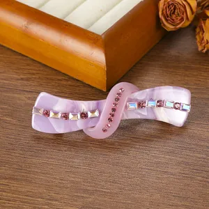 Macro detail of twisted acetate hair clip with pink rhinestones and marble texture