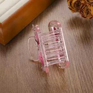Close-up of pink translucent resin hair claw clip with small floral design and rhinestones