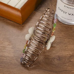 Close-up of large coffee hair claw clip with colorful rhinestones and bow accents