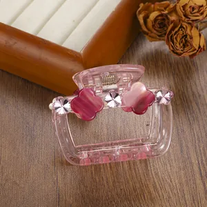 Detail of pink transparent hair claw clip with floral and clover accents on wood