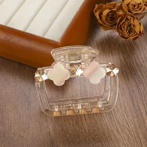 Detailed macro view of a rectangular transparent hair claw with amber crystals and floral petals
