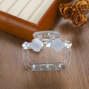 Detailed view of a transparent acrylic hair claw clip with floral accents and gold spring