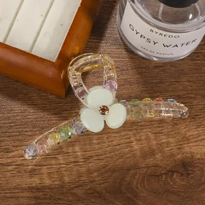 Detail of a large acrylic hair claw clip with colorful beads and a green flower motif
