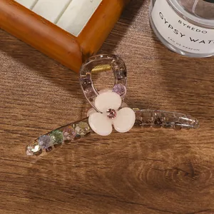 Detailed close-up of amber hair claw with cream flower, pink crystal and colorful beads
