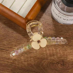 Close-up of a floral clear hair claw clip with colorful beads on a wooden surface