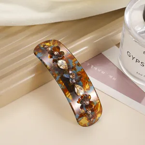 Close-up of tortoiseshell acetate spring hair clip with brown flowers and crystals