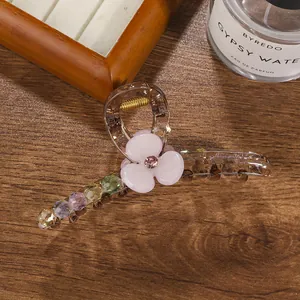 Macro view of amber acrylic hair claw clip with purple flower and rhinestone details