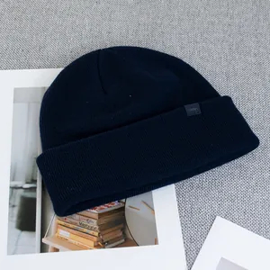 Detailed close-up of navy blue wool knit beanie with woven brand label and rib texture