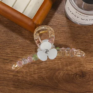 Detail of flower hair claw with matte white petals and multi-colored faceted beads