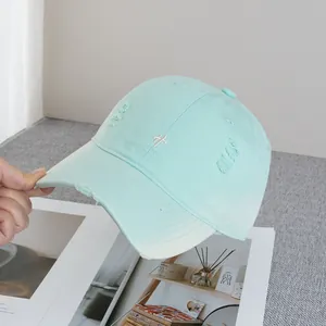 Detail of mint green baseball cap with white embroidery and distressed canvas texture
