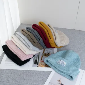 Chunky knit wool beanie with ribbed pattern and brand label shown in various winter colors
