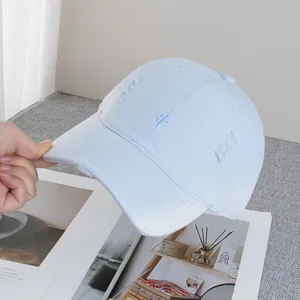 Detail of light blue baseball cap with distressed frayed edges and needlework embroidery
