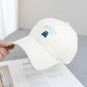 Detailed embroidery of a cute blue bear and text on a white cotton baseball cap